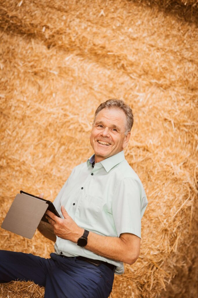 Rainer Liebich vor Stohballen mit einem Tablet.